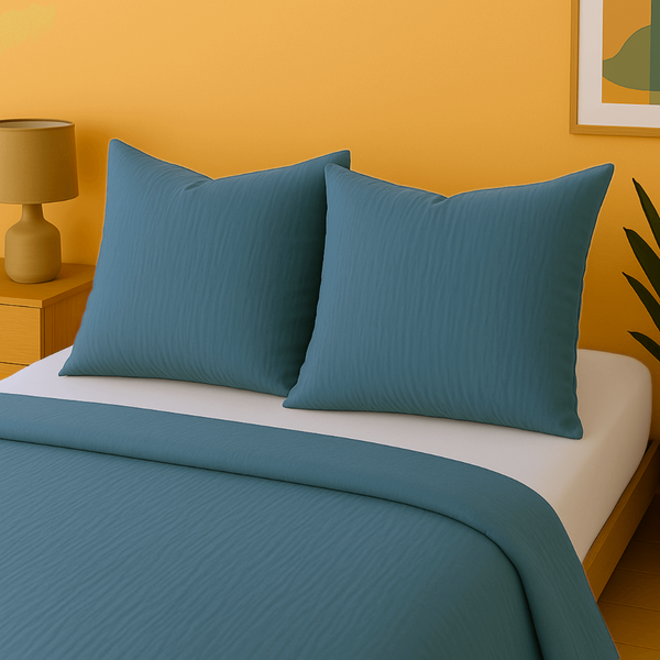 Taies d'oreillers en gaze de coton houz'bed sur un lit moderne avec draps blue et mur jaune.