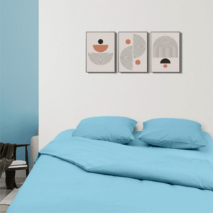 Lit habillé d’une parure unie bleu ciel dans une chambre moderne aux murs blancs et bleus, décorée de trois tableaux graphiques au-dessus de la tête de li houz'bed